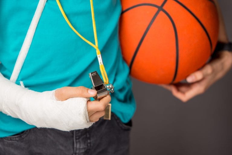 Handsome boy with broken arm over grey background