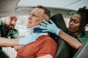 Two doctors examine a man in a car, emphasizing mva rehabilitation and car accident therapy in Calgary